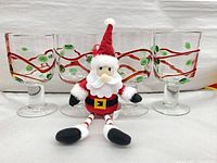 Front view of four goblets with plush Santa doll