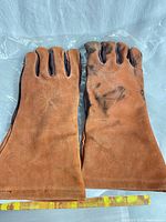 Full view of both brown suede leather garden gloves laid flat