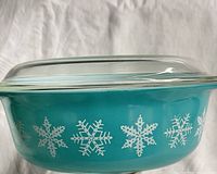 Side view of turquoise Pyrex casserole with snowflake pattern and lid