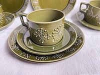 Cup on saucer with side plate, showing relief pattern