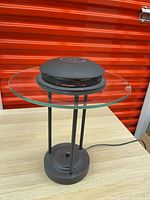 Full view of desk lamp showing glass disc shade, metal dome, base and cord