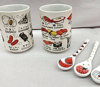 Two sushi-illustrated ceramic cups and three fruit-decorated ceramic spoons