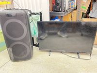 Westinghouse TV and large tower speaker side by side