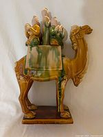 full left-side view of glazed ceramic camel statue on base