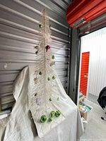 Full view of white minimalist tree with ornaments on quilted base