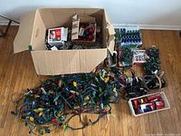 Overview of large box, loose string lights, boxed light sets on floor