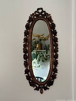 Full view of oval mirror on wall showing entire frame and glass