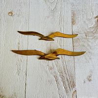 Both brass seagulls on wood background