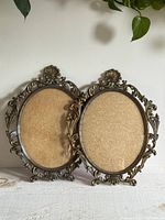 Two matching ornate oval metal frames with convex glass
