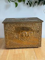 Front view of coal box showing full embossed horse plough scene and lid