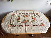 Full view of rectangular beige tablecloth laid flat on table, showing overall design and size