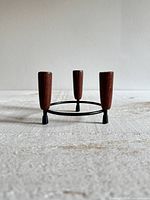 Front angled view of candle holder showing three wooden cups on black metal ring and legs