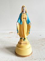 Full view of plastic Virgin Mary music figurine on yellow base