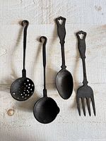 Four cast iron utensils on white wood surface