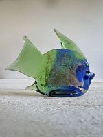 Left profile of green, blue and gold glass fish figurine
