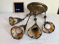 Full chandelier canopy with four pendant arms and shades shown lying on surface