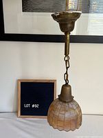 Pendant light with brass hardware and glass shade, full view with measuring board