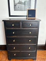 Front view of black distressed tallboy dresser with five drawers