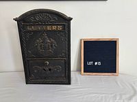Front view of cast iron mailbox showing raised 'LETTERS' and crest