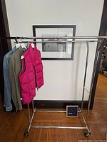 Full view of assembled chrome double-rod clothes rack holding sample garments
