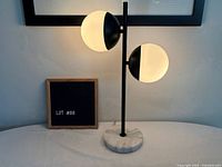 Full view of lamp illuminated showing two bifurcated globes and marble base