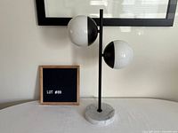 Full view of lamp showing two white globes on black stem with marble base
