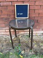 Full view of round glass outdoor side table against brick wall