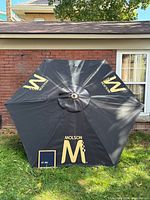 Top view of opened black umbrella showing Molson gold logos