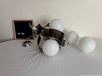 Chandelier resting on table with three attached globes and two loose spare globes