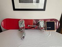 Top of snowboard showing red topsheet and bindings