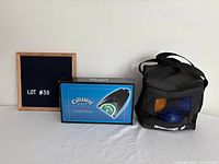 Boxed Callaway putting cup beside Sportcraft bocce ball carry bag