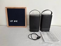 Front view of two Sylvania speakers with charging cable and manual