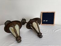 Two hammered metal pendant lanterns lying on table near lot sign
