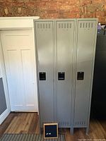 Front view of three gray steel lockers, doors closed