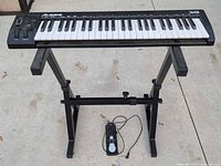 Full view of keyboard on stand with sustain pedal
