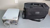 Top view of Epson PowerLite 7800 projector beside carrying case