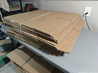 Stack of flattened cardboard boxes bound with white strap