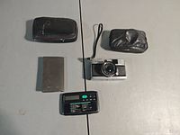 All items laid out: Olympus PEN camera, TI calculator with cover, two pouches/cases