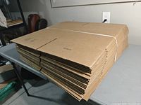 Stack of flat, strapped corrugated boxes on table, showing thickness of bundle