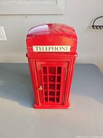 Front view of red telephone booth cabinet showing TELEPHONE decal and door with knob