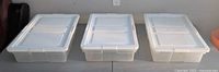 Three identical clear plastic totes with lids side-by-side