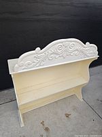 Front view showing ornate crest, cream body, two shelves