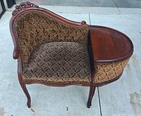 Front view showing carved frame, attached oval side table and patterned upholstery