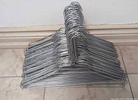 Stack of silver galvanized wire clothes hangers on floor