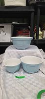 Three light blue ceramic mixing bowls displayed together