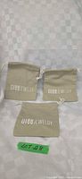Three khaki Glee Jewelry canvas pouches laid flat