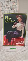 Front view of printed steel Coca-Cola sign with woman drinking, full artwork visible