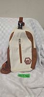 Front view of cream and brown crossbody sling bag with front zip pocket and MK logo patch