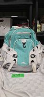 Front view of High Sierra turquoise and white backpack with logo and gear loop