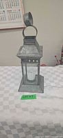 Front view of metal lantern showing glass panels and included candle